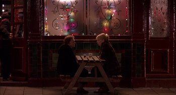 Movie still from “Notes on a Scandal” (2006), directed by Richard Eyre – A man and a woman sitting at a wooden table; Wide shot, Over the shoulder angle