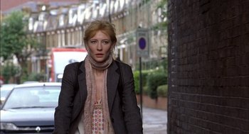 Movie still from “Notes on a Scandal” (2006), directed by Richard Eyre – A woman wearing a jacket and scarf walking down a street; Close Up shot, Low angle