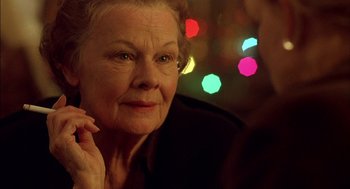 Movie still from “Notes on a Scandal” (2006), directed by Richard Eyre – An older woman looking at the camera while holding a cell phone to her ear; Close Up shot, Over the shoulder angle