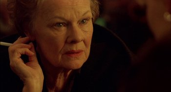 Movie still from “Notes on a Scandal” (2006), directed by Richard Eyre – An older woman looking at the camera while sitting down; Close Up shot, Over the shoulder angle