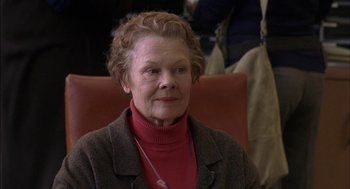 Movie still from “Notes on a Scandal” (2006), directed by Richard Eyre – An older woman wearing a red sweater and a brown jacket; Close Up shot, Over the shoulder angle