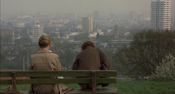 Movie still from “Notes on a Scandal” (2006), directed by Richard Eyre – Two people sitting on a park bench looking out at a city; Wide shot, High angle
