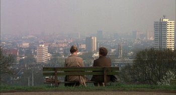 Movie still from “Notes on a Scandal” (2006), directed by Richard Eyre – Two people sitting on a bench looking out over a city; Wide shot, High angle