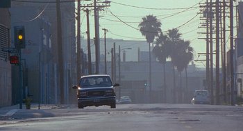 Movie still from “Nothing to Lose” (1997), directed by Steve Oedekerk – A car driving down a street near power lines and traffic lights; Wide shot, Low angle
