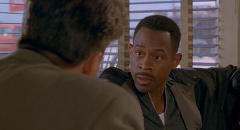 Movie still from “Nothing to Lose” (1997), directed by Steve Oedekerk – A man sitting in front of another man in front of a window; Close Up shot, Over the shoulder angle