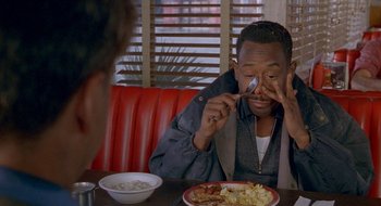 Movie still from “Nothing to Lose” (1997), directed by Steve Oedekerk – A man sitting in front of a plate of food at a restaurant; Close Up shot, High angle