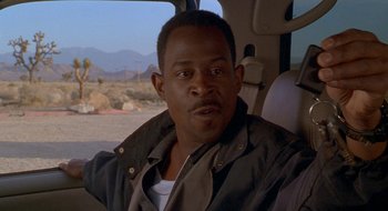 Movie still from “Nothing to Lose” (1997), directed by Steve Oedekerk – A man sitting in the back seat of a car; Close Up shot, Over the shoulder angle