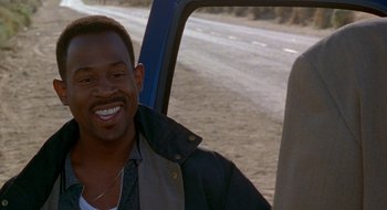 Movie still from “Nothing to Lose” (1997), directed by Steve Oedekerk – A man smiling while sitting in the back of a truck; Close Up shot, Over the shoulder angle