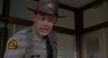Movie still from “Nothing to Lose” (1997), directed by Steve Oedekerk – A man in a sheriff's hat and tie; Close Up shot, Over the shoulder angle