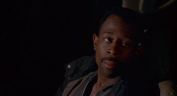 Movie still from “Nothing to Lose” (1997), directed by Steve Oedekerk – A person sitting in a room; Close Up shot, Over the shoulder angle