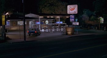 Movie still from “Nothing to Lose” (1997), directed by Steve Oedekerk – A car parked in front of an indian chief gas station at night; Extreme Wide shot, High angle