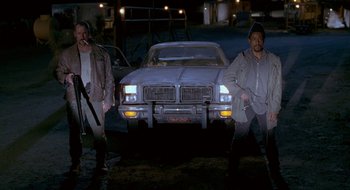 Movie still from “Nothing to Lose” (1997), directed by Steve Oedekerk – A couple of men standing in front of a car at night; Wide shot, Low angle
