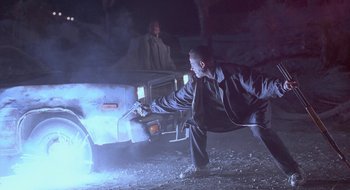 Movie still from “Nothing to Lose” (1997), directed by Steve Oedekerk – A man in black jacket standing in front of a truck at night; Wide shot, Low angle