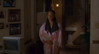 Movie still from “Nothing to Lose” (1997), directed by Steve Oedekerk – A woman standing in a room wearing a robe; Medium shot, Over the shoulder angle
