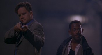 Movie still from “Nothing to Lose” (1997), directed by Steve Oedekerk – Two men standing next to each other in a dark room; Medium shot, Low angle