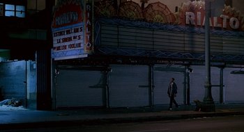 Movie still from “Nothing to Lose” (1997), directed by Steve Oedekerk – A man walking down the street in front of a movie theater at night; Extreme Wide shot, Low angle