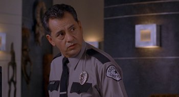 Movie still from “Nothing to Lose” (1997), directed by Steve Oedekerk – A police officer in uniform is standing in a room; Close Up shot, Over the shoulder angle