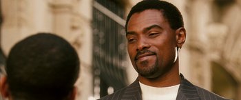 Movie still from “Notorious” (2009), directed by George Tillman Jr. – A person wearing a suit and smiling; Close Up shot, Over the shoulder angle