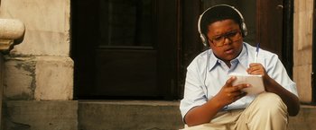 Movie still from “Notorious” (2009), directed by George Tillman Jr. – A person wearing headphones and sitting on a bench; Medium shot, High angle