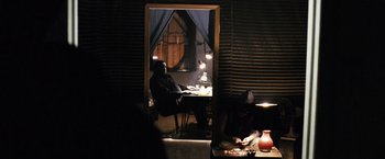 Movie still from “Notorious” (2009), directed by George Tillman Jr. – A man sitting at a table in front of an open door; Wide shot, Over the shoulder angle