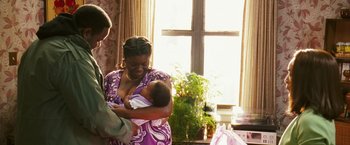 Movie still from “Notorious” (2009), directed by George Tillman Jr. – A woman holding a baby in her arms; Medium shot, Over the shoulder angle