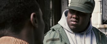 Movie still from “Notorious” (2009), directed by George Tillman Jr. – A man wearing a hat and a green jacket talking to another man; Close Up shot, Over the shoulder angle