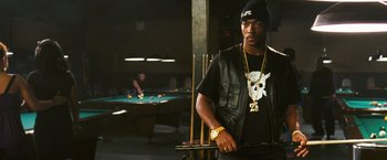 Movie still from “Notorious” (2009), directed by George Tillman Jr. – A man holding a gun while standing next to a pool table; Medium shot, Over the shoulder angle