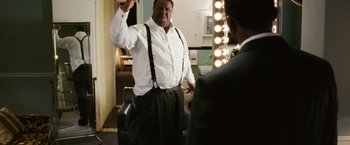 Movie still from “Notorious” (2009), directed by George Tillman Jr. – A man standing in front of a mirror in a room; Medium shot, Low angle