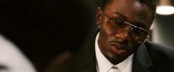 Movie still from “Notorious” (2009), directed by George Tillman Jr. – A person wearing glasses and a suit; Close Up shot, Over the shoulder angle