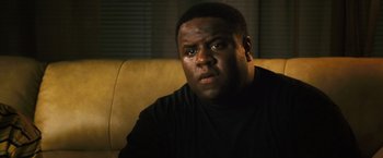 Movie still from “Notorious” (2009), directed by George Tillman Jr. – A man sitting on a couch in a room; Close Up shot, Low angle