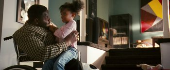 Movie still from “Notorious” (2009), directed by George Tillman Jr. – A little girl sitting on a man's lap in front of a tv; Medium shot, Over the shoulder angle