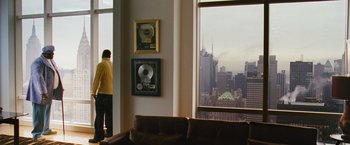Movie still from “Notorious” (2009), directed by George Tillman Jr. – A man standing in front of a window looking out at a city; Extreme Wide shot, Over the shoulder angle