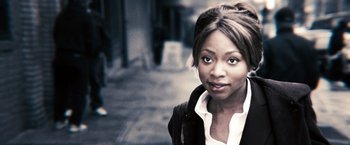 Movie still from “Notorious” (2009), directed by George Tillman Jr. – A woman standing on the side of the street; Close Up shot, Over the shoulder angle