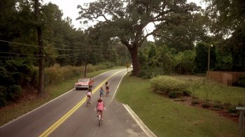 Movie still from “Now and Then” (1995), directed by Lesli Linka Glatter – A group of bicyclists riding down a road; Extreme Wide shot, High angle