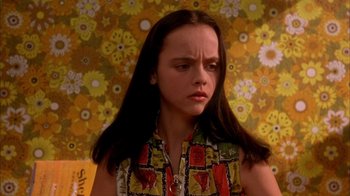 Movie still from “Now and Then” (1995), directed by Lesli Linka Glatter – A young woman with long black hair in front of a floral wallpaper; Close Up shot, High angle