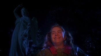 Movie still from “Now and Then” (1995), directed by Lesli Linka Glatter – A young girl smiling in front of a statue; Medium shot, Low angle