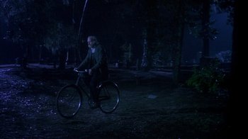 Movie still from “Now and Then” (1995), directed by Lesli Linka Glatter – A man riding a bike in the dark at night; Wide shot, High angle
