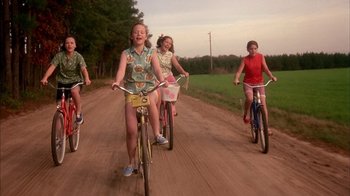 Movie still from “Now and Then” (1995), directed by Lesli Linka Glatter – A group of people riding bikes down a dirt road; Wide shot, Low angle