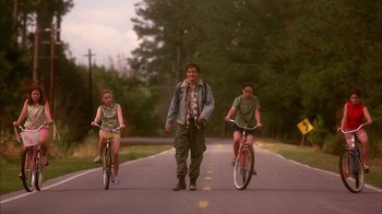 Movie still from “Now and Then” (1995), directed by Lesli Linka Glatter – A man and two young girls riding bikes down a street; Wide shot, Low angle