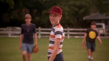 Movie still from “Now and Then” (1995), directed by Lesli Linka Glatter – A young boy wearing a red hat is playing baseball; Medium shot, Low angle