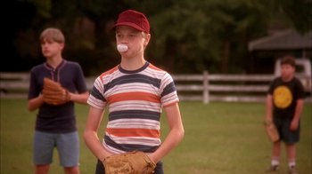 Movie still from “Now and Then” (1995), directed by Lesli Linka Glatter – A young boy with a baseball glove and a ball in his mouth; Medium shot, Low angle