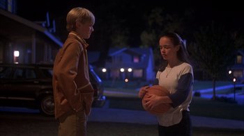 Movie still from “Now and Then” (1995), directed by Lesli Linka Glatter – A boy and a girl holding a basketball in the dark; Medium shot, Over the shoulder angle