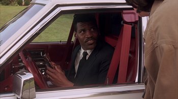 Movie still from “Now and Then” (1995), directed by Lesli Linka Glatter – A man sitting in the driver's seat of a car holding a cell phone; Close Up shot, Over the shoulder angle