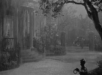 Movie still from “Now, Voyager” (1942), directed by Irving Rapper – A black - and - white photo of a person in the rain; Extreme Wide shot, High angle