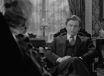 Movie still from “Now, Voyager” (1942), directed by Irving Rapper – An older man sitting in front of an older woman in a chair; Medium shot, Over the shoulder angle