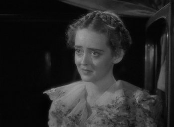 Movie still from “Now, Voyager” (1942), directed by Irving Rapper – A young woman in a floral dress looking at the camera; Close Up shot, High angle