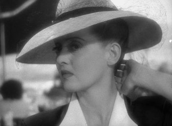 Movie still from “Now, Voyager” (1942), directed by Irving Rapper – A black and white photo of a woman wearing a hat; Close Up shot, High angle
