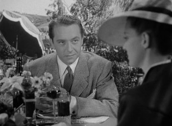 Movie still from “Now, Voyager” (1942), directed by Irving Rapper – A black and white photo of a man and a woman at an outdoor table; Medium shot, Over the shoulder angle