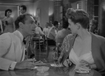 Movie still from “Now, Voyager” (1942), directed by Irving Rapper – A man and a woman sitting at a table in front of each other; Medium shot, Over the shoulder angle