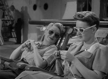 Movie still from “Now, Voyager” (1942), directed by Irving Rapper – A couple of women sitting on a chair knitting; Medium shot, High angle